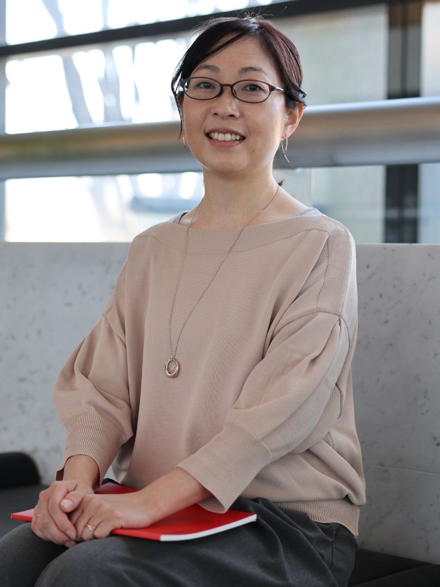 赤い冊子を手に微笑む望月あさみ